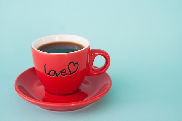 Ciérrese para arriba de la taza roja de café caliente con la palabra AMOR en fondo del color en colores pastel