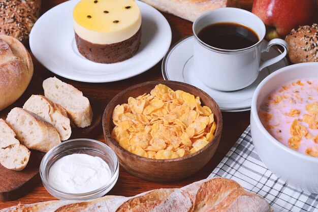 Foto ciérrese para arriba de la torta de la fruta de la pasión, de la tostada, del café, del yogur, de los cereales.