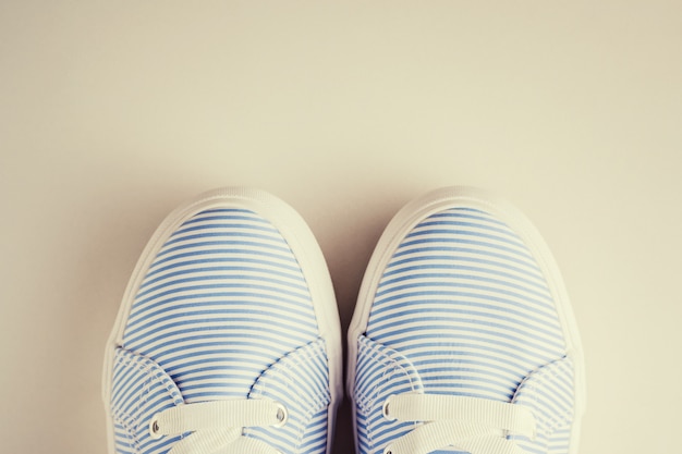 Ciérrese para arriba de zapatillas de deporte femeninas rayadas azules en una opinión superior del fondo blanco. Fondo plano laico minimalista, foto en tonos