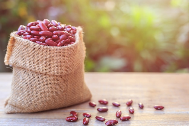 Ciérrese encima de alubia roja en pequeño saco marrón en la tabla de madera