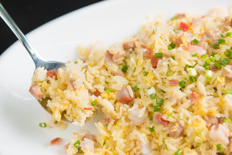 Foto ciérrese encima del arroz frito en la cuchara en el plato blanco en fondo negro