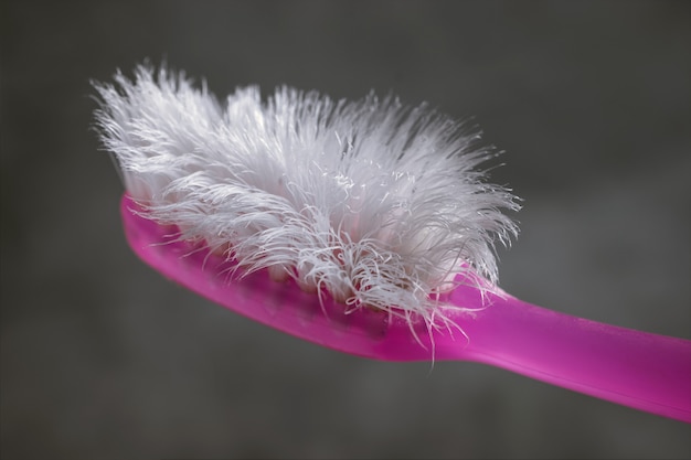 Ciérrese encima de cepillo de dientes rosado usado con el fondo del cemento.