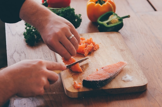 Ciérrese encima del cocinero que corta salmones en borad de madera.