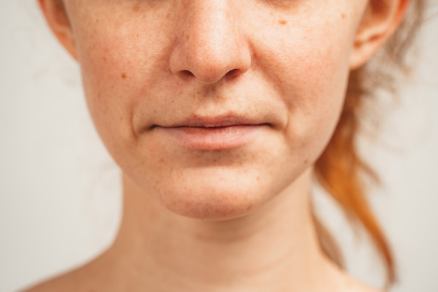 Ciérrese encima de la foto de la cara inferior de la mujer joven pelirroja. Aislado sobre fondo blanco. Belleza y salud natural.