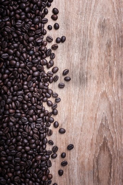 Ciérrese encima de los granos de café en el fondo de madera, composición con el espacio libre de la madera