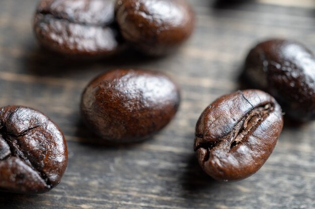 Ciérrese encima de los granos de café en la tabla de madera.