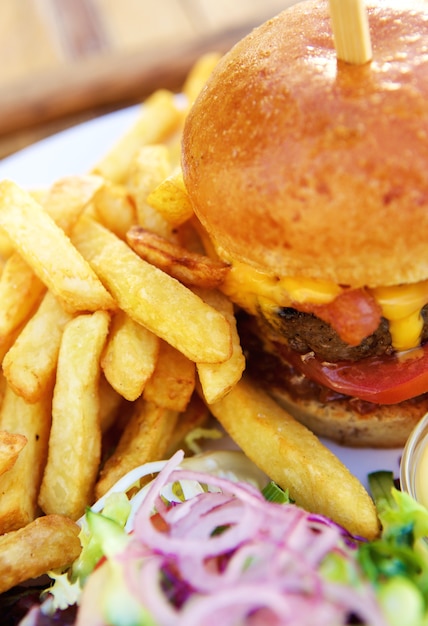 Foto ciérrese encima de la hamburguesa del queso con las fritadas y una ensalada sana