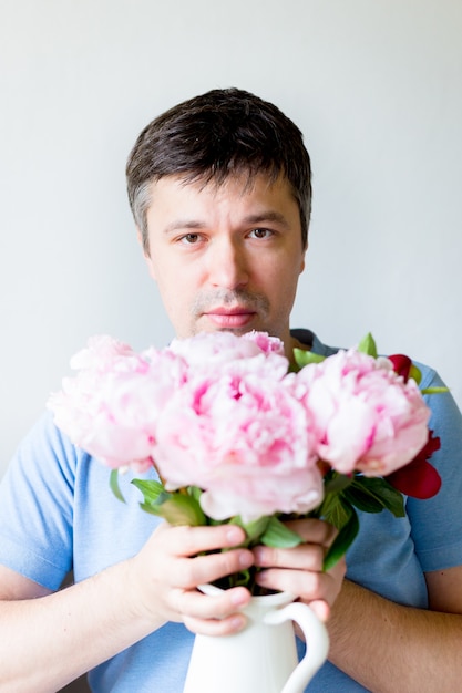 Foto ciérrese encima del hombre joven que sostiene las flores. el hombre con una máscara médica antivirus sostiene un ramo de flores. recuperación del coronavirus. detener la pandemia de covid-19