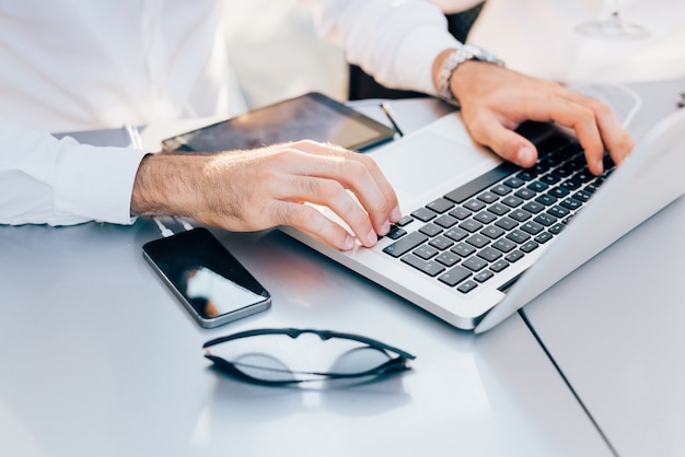 Ciérrese encima de la mano del hombre de negocios usando la computadora