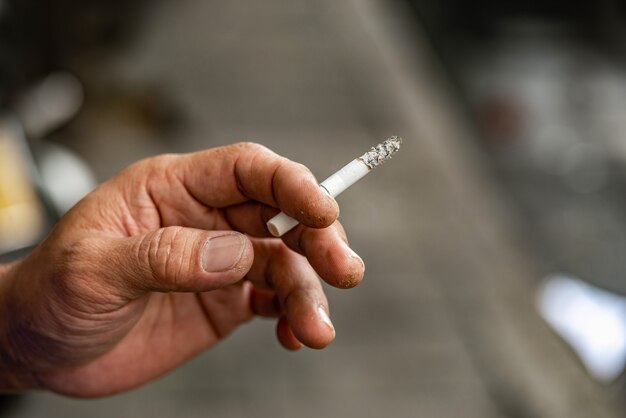 Foto ciérrese encima de la mano masculina que sostiene un cigarrillo, sucio.