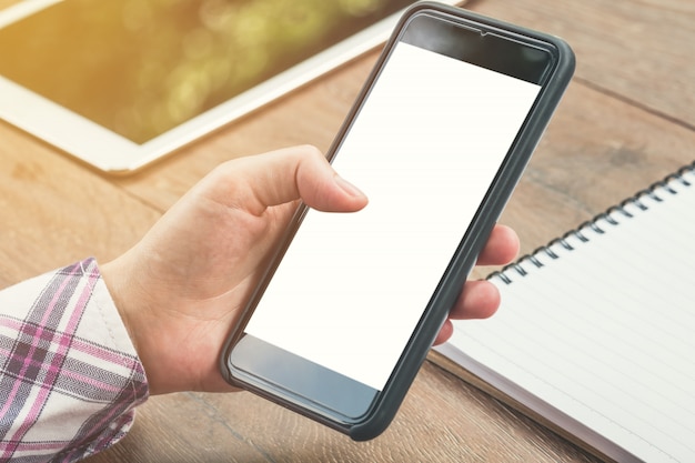 Foto ciérrese encima de la mano de la mujer que sostiene la pantalla de visualización en blanco del teléfono blanco con la vendimia entonada.