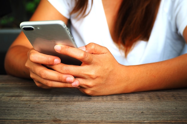 Ciérrese encima de la mano de la mujer usando el teléfono móvil elegante.