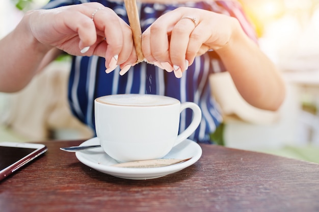 Foto ciérrese encima de las manos con el azúcar y la taza de café.