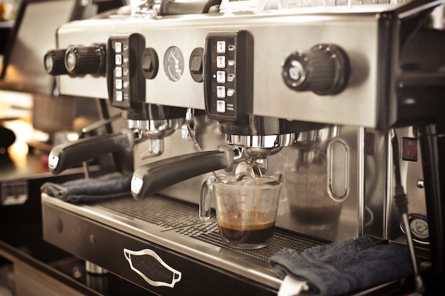 Ciérrese encima de las manos del barista que hacen el café por la máquina en café de café