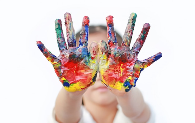 Foto ciérrese encima de las manos del niño pintadas en las pinturas coloridas aisladas.