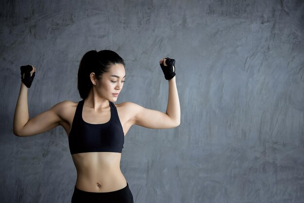 Ciérrese encima de la muchacha asiática hermosa del deporte en la pared del gimnasio Tailandia ama la salud Concepto de entrenamiento de mujer delgada Mostrar paquete de seis