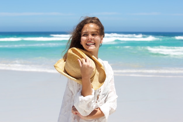 Ciérrese encima de la mujer joven despreocupada que sonríe en la playa