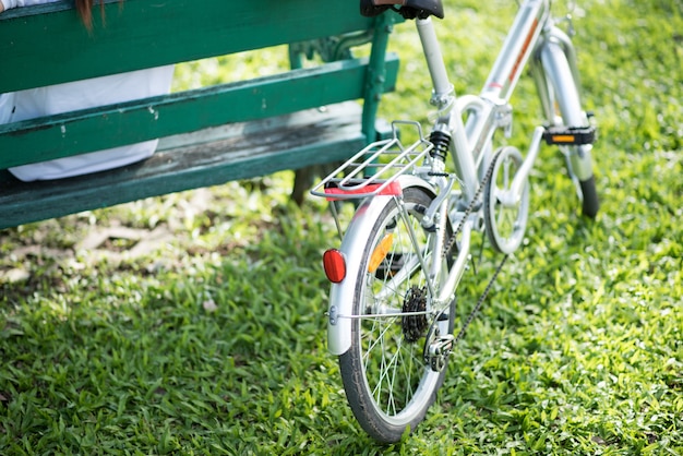 Ciérrese encima de mujer joven que monta la bicicleta de la bici en el parque público natural