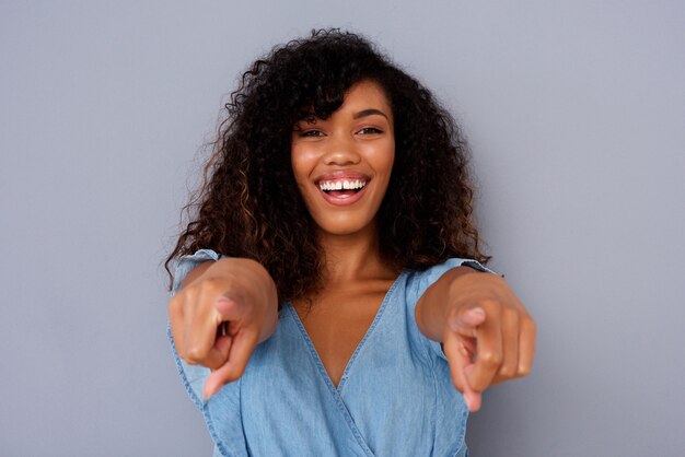 Ciérrese encima de la mujer negra joven hermosa que sonríe y que señala los fingeres