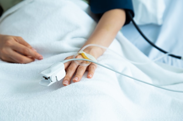 Ciérrese encima del paciente asiático de la mujer de la mano. Centrarse en la mano de un paciente en la sala del hospital.