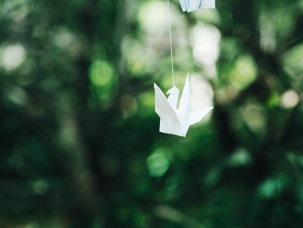 Ciérrese encima de pájaro del origami en el jardín.