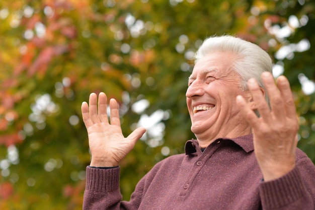 Foto ciérrese encima del retrato del hombre mayor que presenta en fondo borroso del parque del otoño