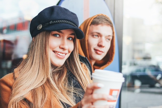 Ciérrese encima del retrato de la joven pareja feliz en los amigos adolescentes del amor vestidos en estilo casual caminando juntos en la calle de la ciudad en la temporada de frío