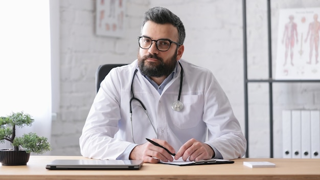 Foto ciérrese encima del retrato del médico de cabecera guapo adulto en el consultorio médico.