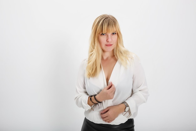 Ciérrese encima del retrato del modelo de la muchacha rubia en suéter de lana blanco en el fondo blanco en estudio