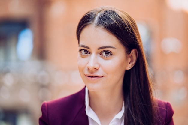 Ciérrese encima del retrato de la morenita hermosa con el pelo largo y los ojos grandes vestidos con el traje púrpura que mira con confianza. Concepto de gente de negocios