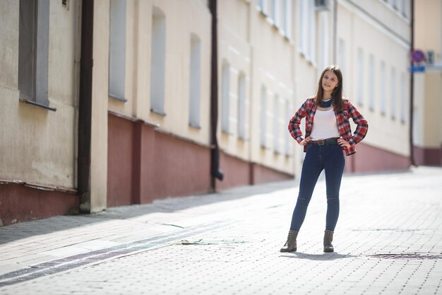 Ciérrese encima del retrato de la muchacha hermosa adolescente en camisa a cuadros brillante en fondo urbano de la calle