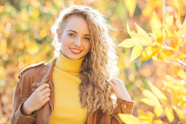 Ciérrese encima del retrato de la muchacha rubia hermosa en otoño. Elegante jovencita en el parque. Hermosa chica rubia al aire libre.