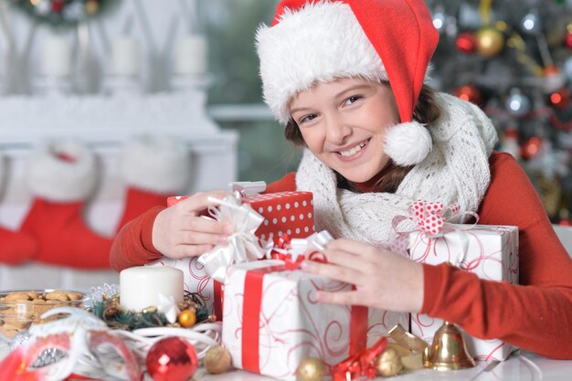 Ciérrese encima del retrato de la muchacha en el sombrero de Papá Noel con los regalos