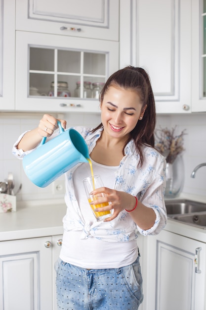 Ciérrese encima del retrato de la mujer atractiva joven que bebe el jugo fresco