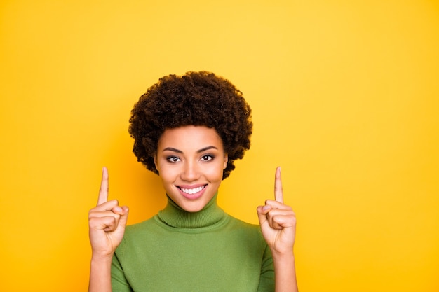 Ciérrese encima del retrato de la mujer bastante atractiva linda alegre que señala hacia arriba con los dedos índices sonriendo toothily.