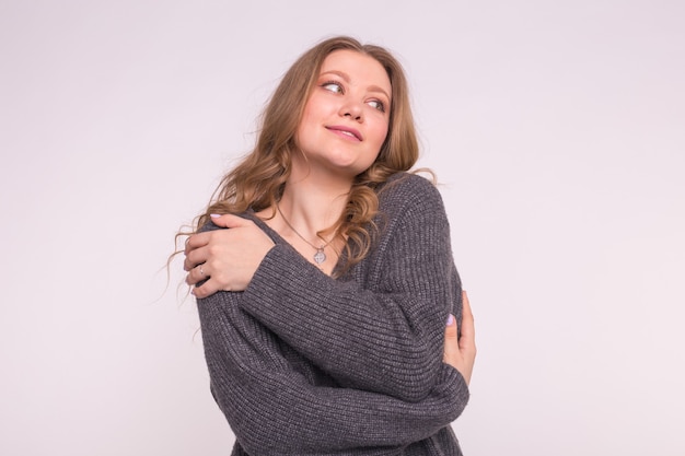 Ciérrese encima del retrato de la mujer caucásica tierna con el pelo rizado que lleva la rebeca gris en blanco.