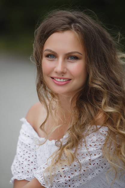 Ciérrese encima del retrato de una mujer hermosa del pelo rizado. Hermosa mujer al aire libre en el parque de verano. Jovencita en la naturaleza