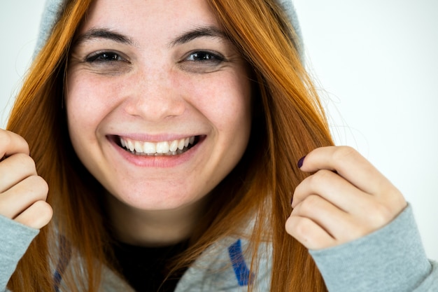 Foto ciérrese encima del retrato de la mujer sonriente feliz del pelirrojo joven que lleva el jersey caliente de la sudadera con capucha.