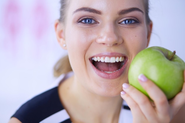 Ciérrese encima del retrato de la mujer sonriente sana con la manzana verde