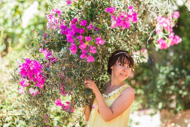 Ciérrese encima del retrato romántico de la mujer elegante hermosa en árboles en flor