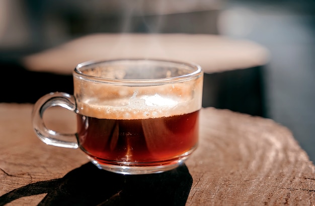 Ciérrese encima de la taza de café de cristal en la tabla de madera.