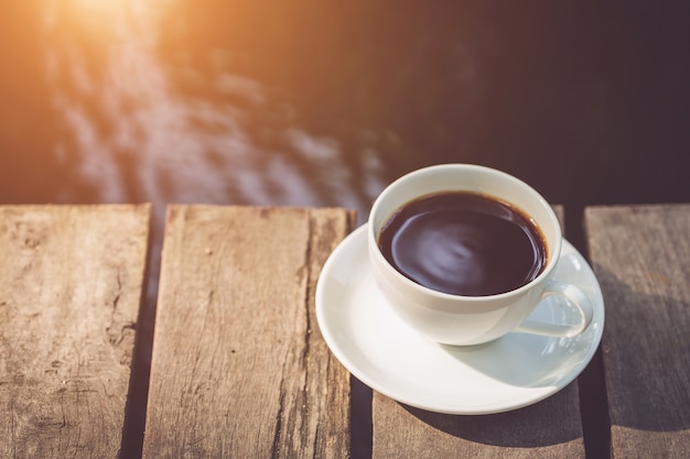 Ciérrese encima de la taza de café con leche en el jardín en el tiempo de mañana