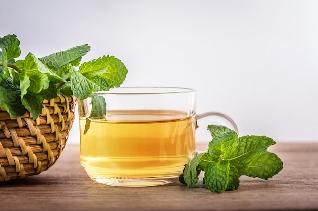 Ciérrese encima de una taza de cristal de té de la menta con las hojas frescas verdes de la hierbabuena