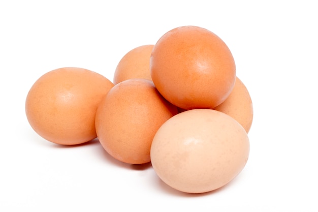 Ciérrese encima de vista de una pila de huevos crudos del pollo aislados en un fondo blanco.