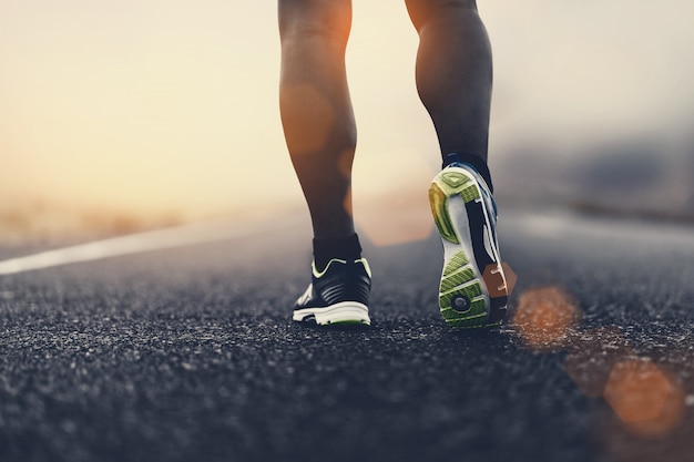 Ciérrese encima de los zapatos del deporte de un corredor en el camino para la forma de vida sana de la aptitud.