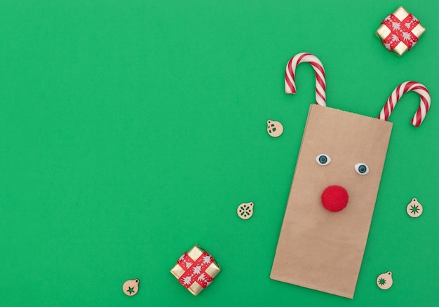 Ciervos de Navidad hechos de bolsa de compras artesanales y dos bastones de Navidad con decoración de Navidad sobre fondo verde.