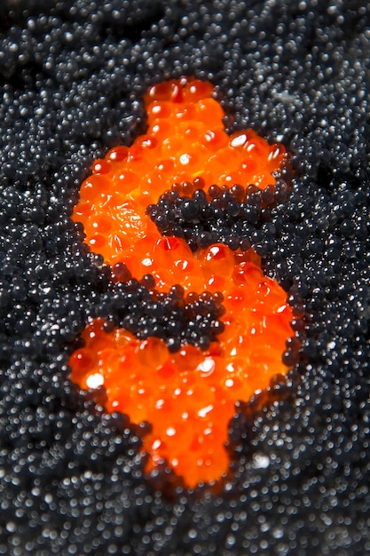 Cifrão de caviar vermelho em um fundo de caviar preto