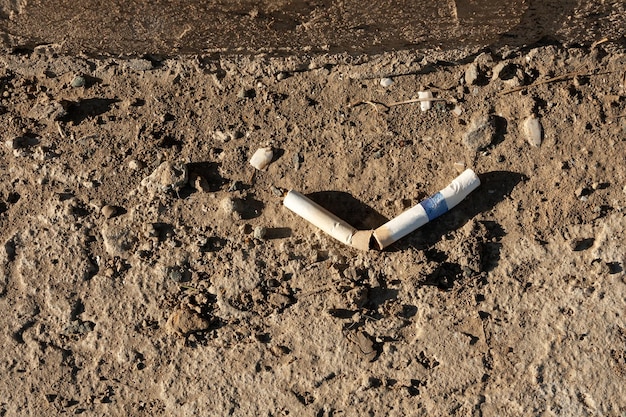 Un cigarrillo ahumado roto yace en el suelo contaminación ambiental