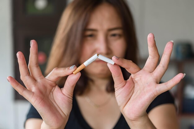 Cigarrillo aplastante de mano de mujer asiáticaDejar el concepto de adicciónDía sin tabacoConcepto de no fumar