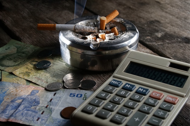 Cigarrillo y calculadora con dinero